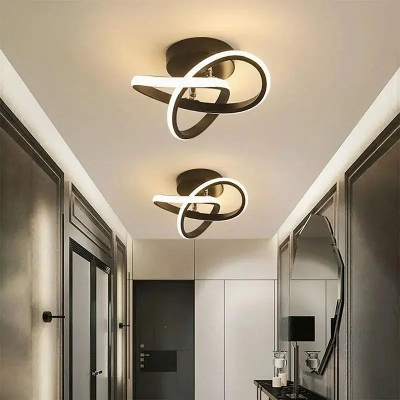 LED ceiling light fixtures with intertwined black metal rings and white LED strips; two fixtures in a modern hallway.
