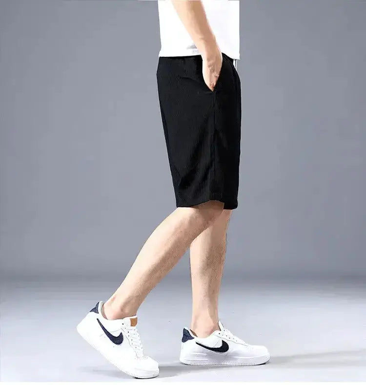 Men's black loose-fit casual shorts paired with white Nike sneakers featuring a black swoosh