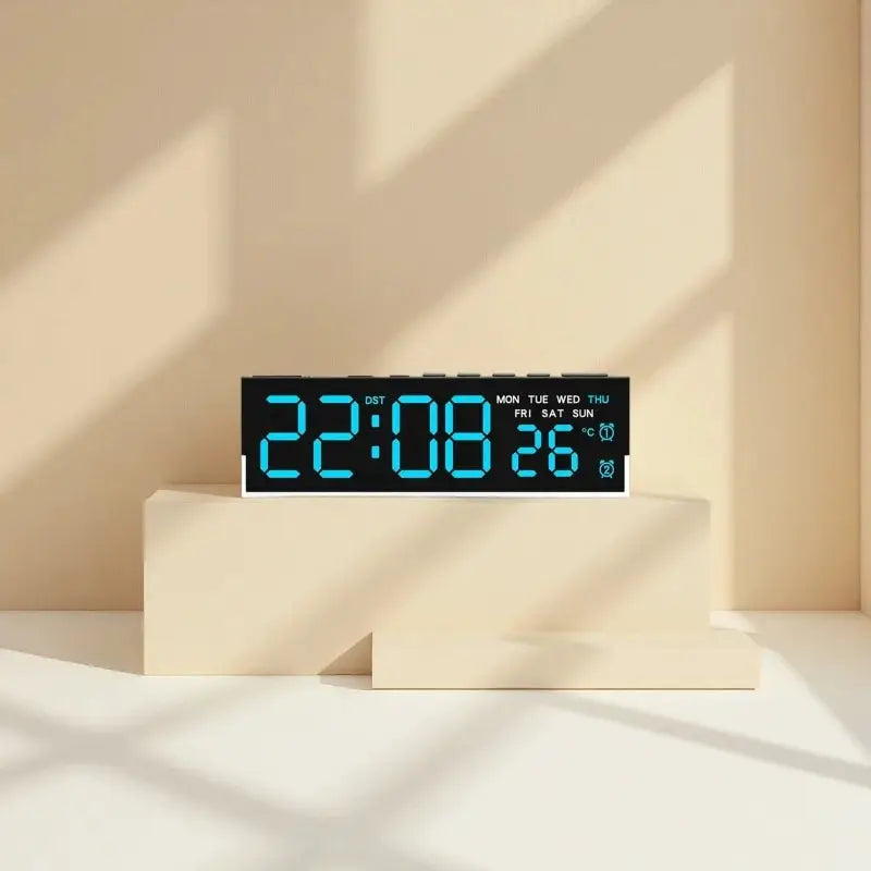 USB powered digital alarm clock with blue LED digits on a black display, placed on a white pedestal.