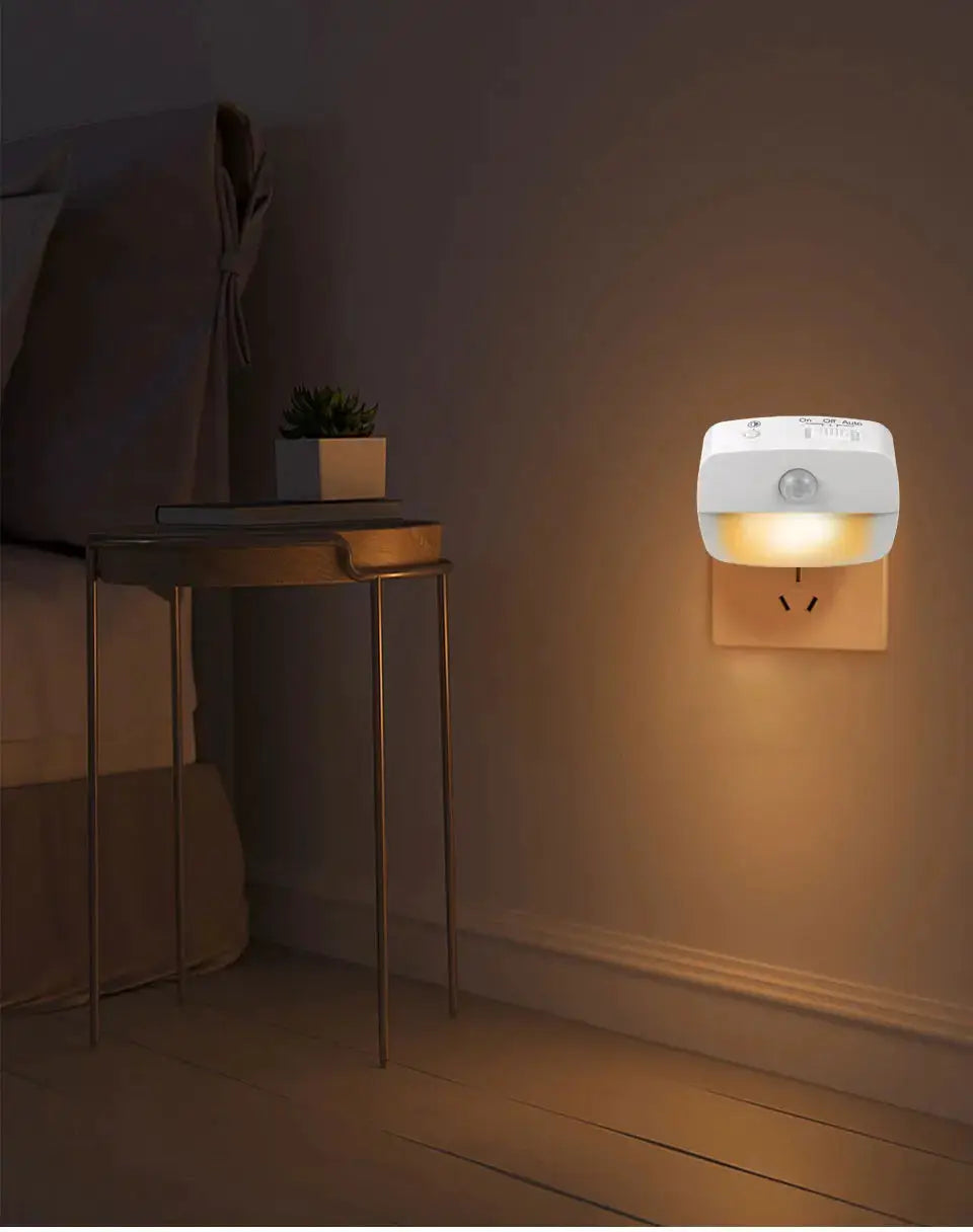 Wireless LED motion sensor night light, white plastic, plug-in wall unit with warm amber glow for bedroom