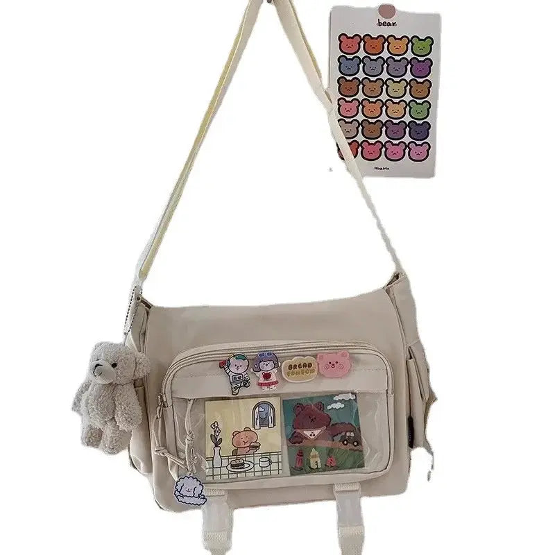 Beige large-capacity crossbody canvas bag with front pockets, patches and plush bear keychain