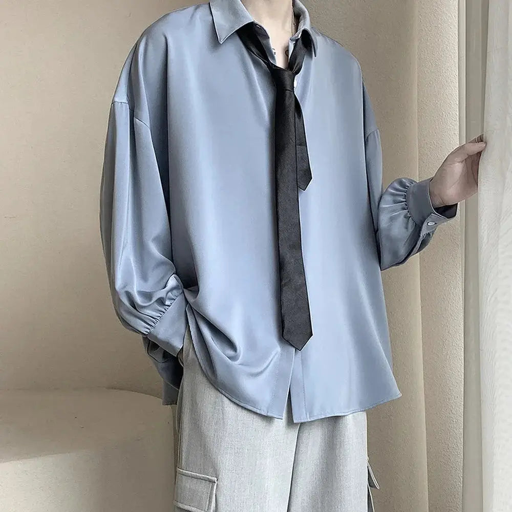 Oversized light blue satin-like men's shirt with a black tie, paired with gray cargo pants.