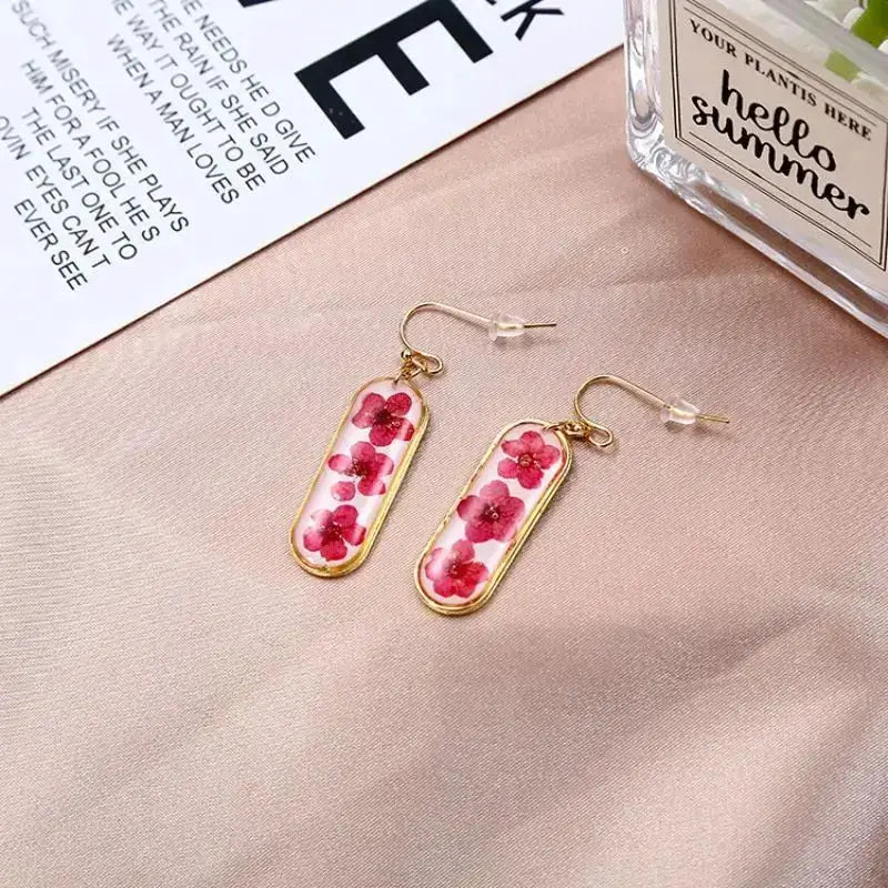 Pressed flower epoxy resin earrings by Simples Market, pair with pink flowers in gold-tone frames