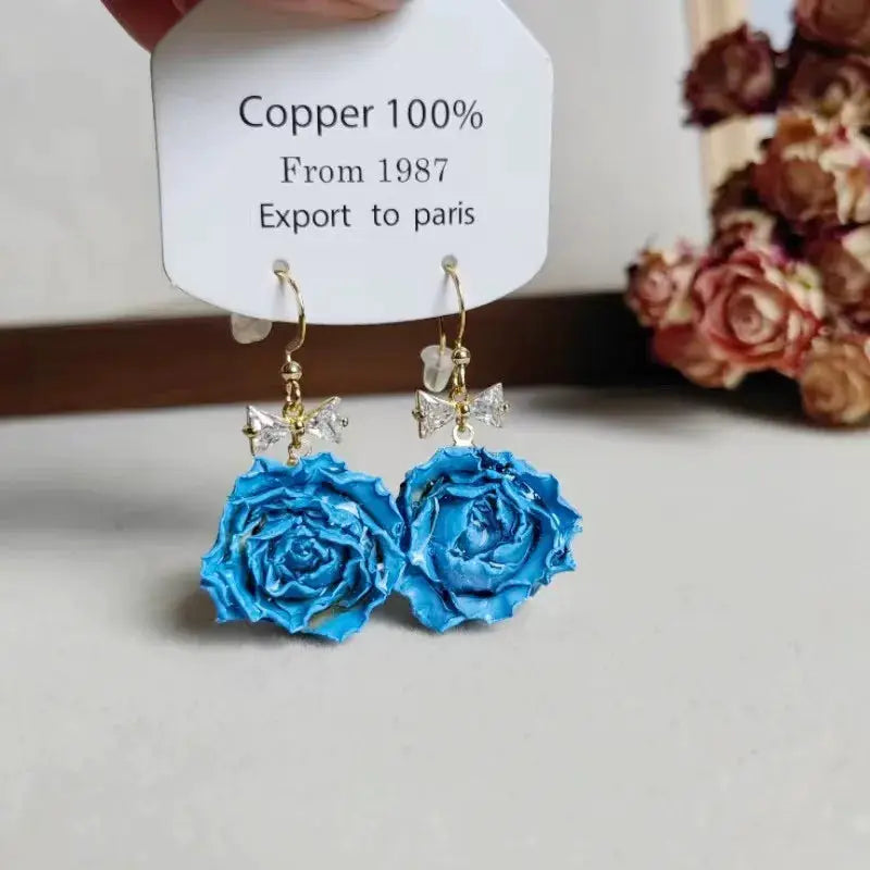 Blue rose epoxy resin long earrings pair with crystal bow accents on gold hooks; Simples Market
