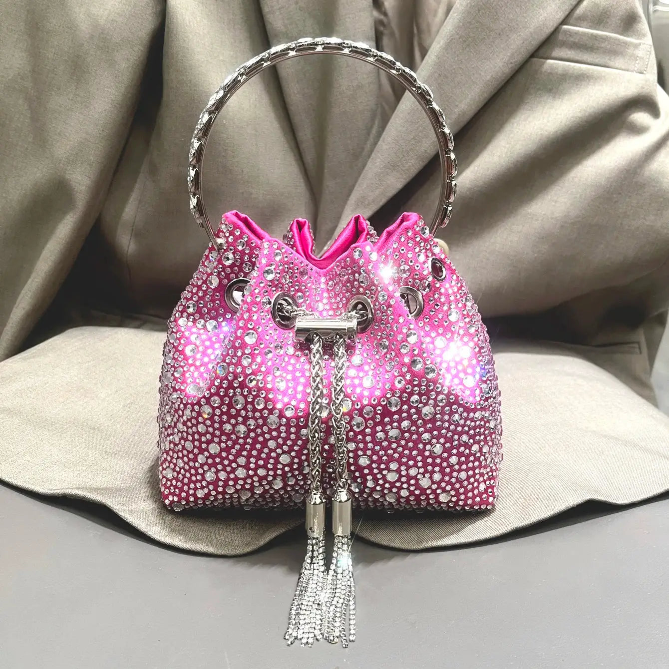 Pink rhinestone evening clutch bag with crystal embellishments, silver ring handle, and tassel fringe