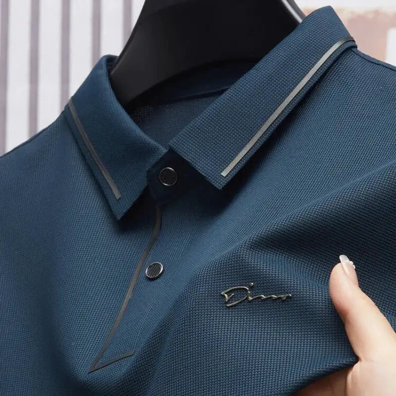 Men's polo shirt in navy blue with textured fabric and small metal logo on chest; business casual golf style.