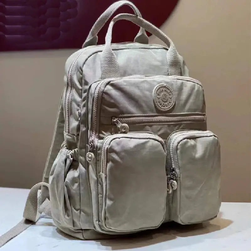 Fashion women's backpack in light gray nylon with multiple zip pockets and top handles