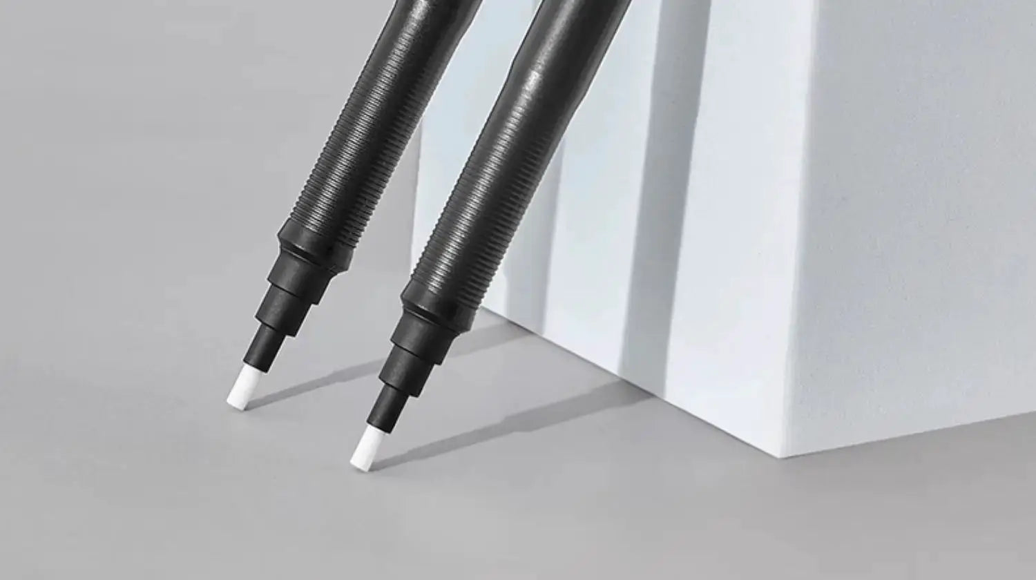 Two black Faber-Castell precision tip pen-style retractable erasers with white 2.5mm tips