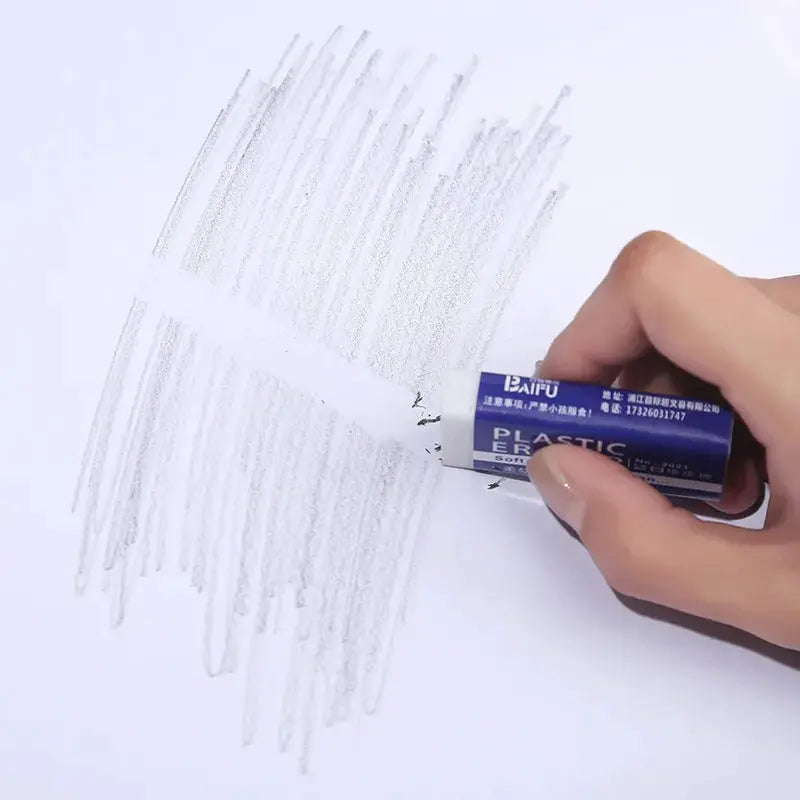 2B eraser by Simples Market with blue wrapper, held to erase pencil marks on white paper
