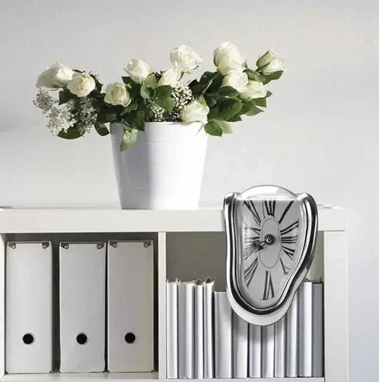 Simples Market surreal melting clock wall clock in white with Roman numerals on a shelf beside a white vase of roses