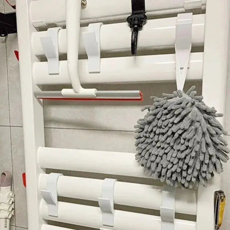 White bathroom towel rack with rails and hooks, gray microfiber duster hanging.