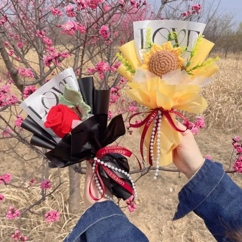 Two Simples Market stuffed plant bouquets; black wrap with red rose, yellow wrap with large center bloom, pearl ribbons