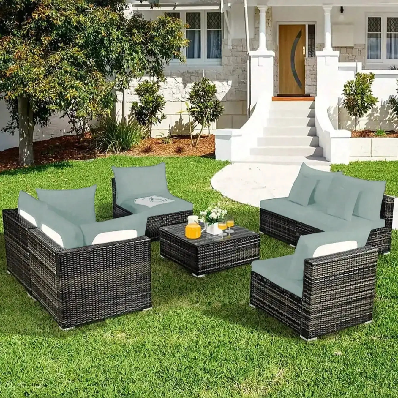 Outdoor sofa cushion set on wicker patio furniture with blue cushions around a coffee table on green lawn.