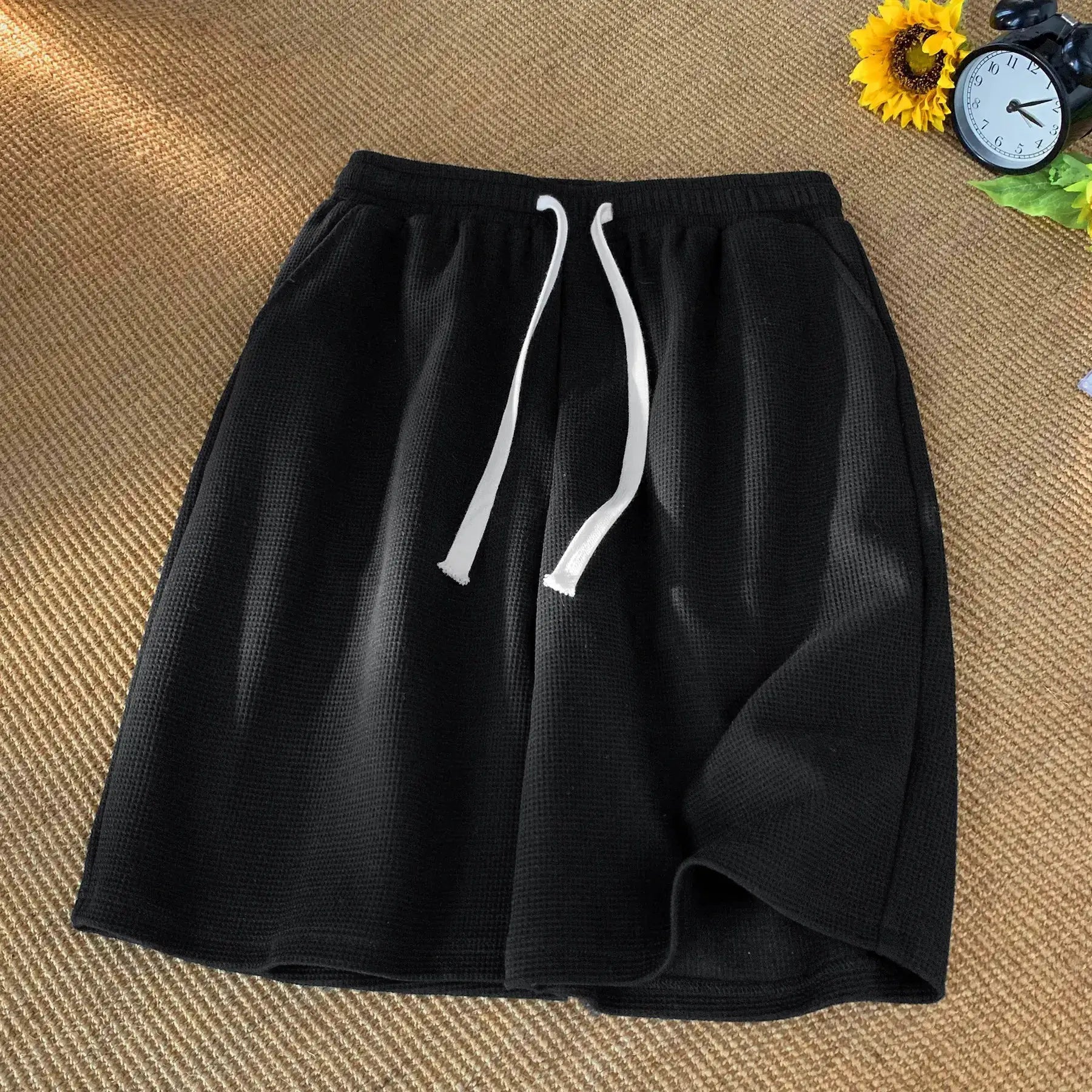Men's waffle shorts, black with white drawstrings, loose-fit lightweight beachwear.