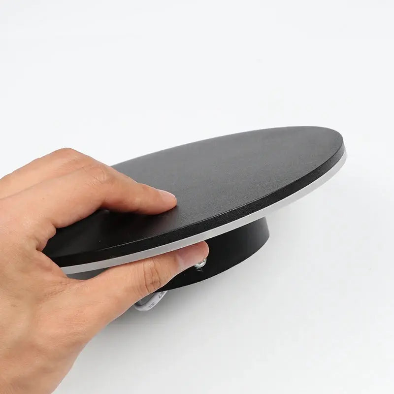 Indoor LED wall lamp in round black aluminum finish being held by hand