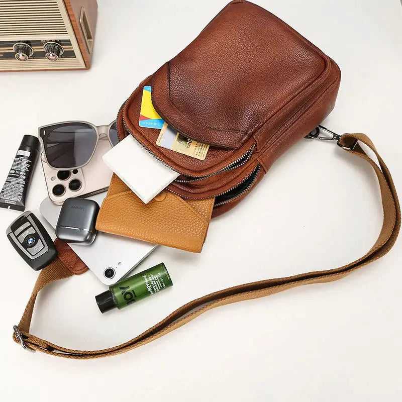 Simples Market brown genuine leather chest bag with long strap; large-capacity crossbody with cards and phone visible.