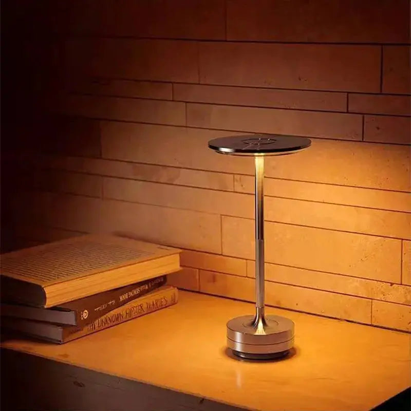 Simples Market wireless decorative table lamp; chrome metal, circular top, warm amber glow on wooden desk