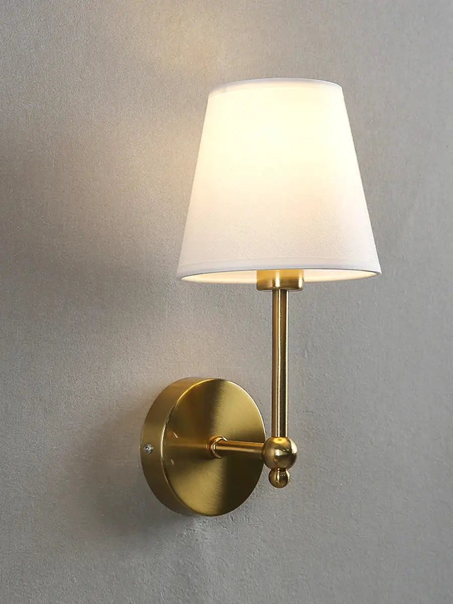 Wall sconce by Simples Market in brass with white fabric shade