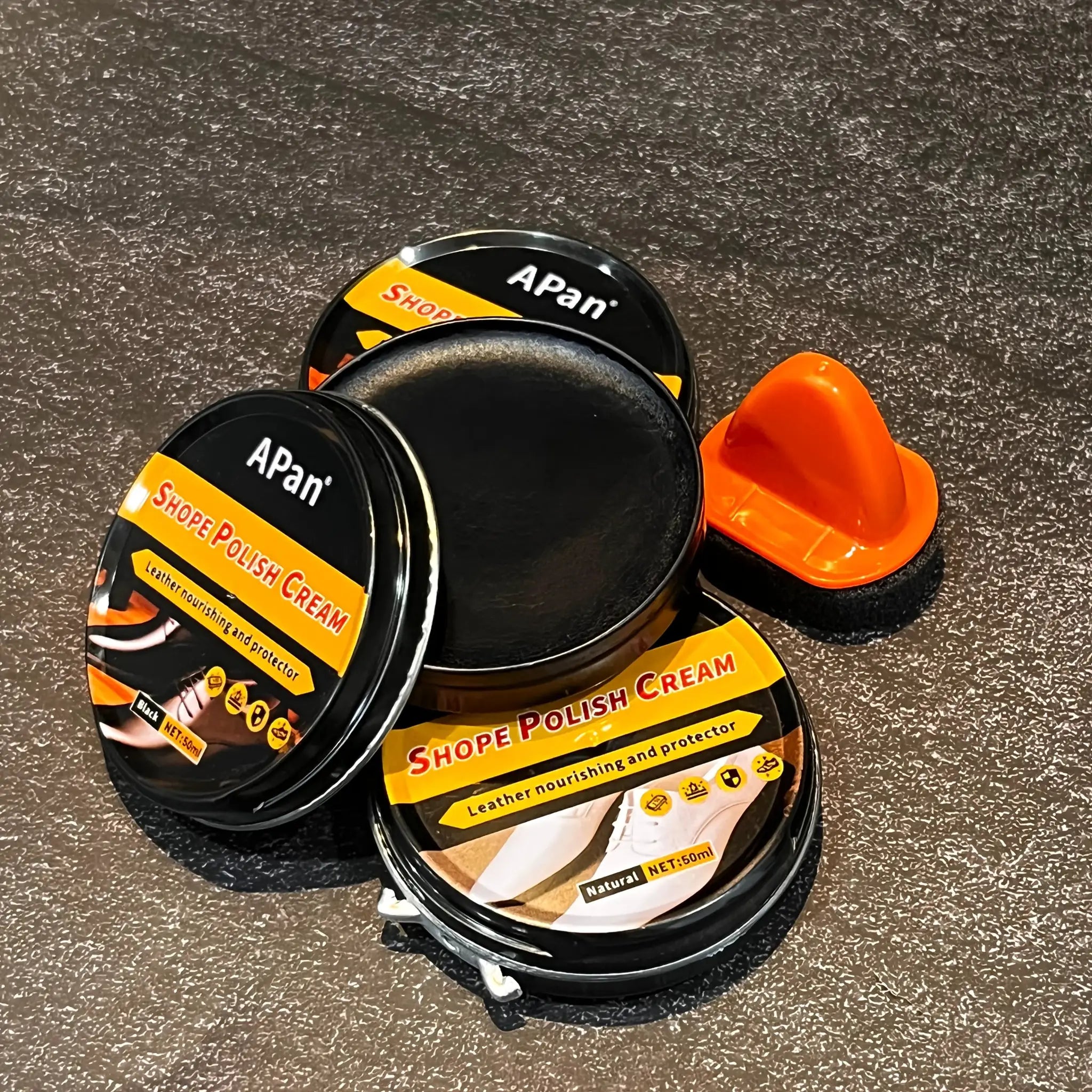 Faux leather shoe polishing kit: black tins with orange labels Shoe Polish Cream, stacked with orange gloves.