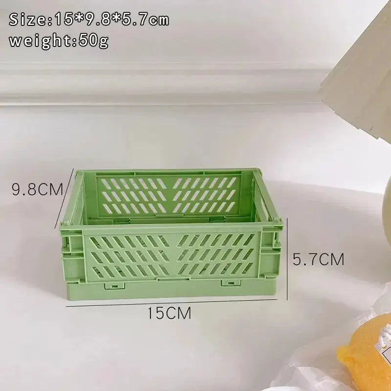 Green plastic storage basket by Simples Market; foldable desktop organizer with perforated sides, 15 x 9.8 x 5.7 cm.