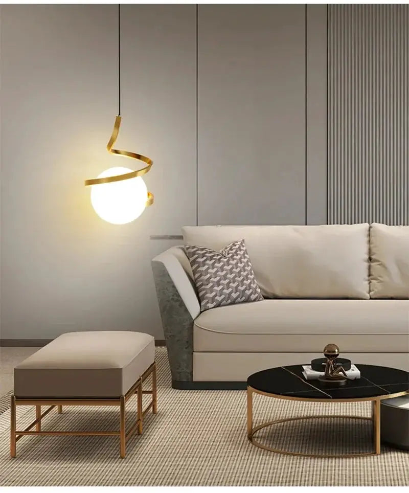 Nordic LED Pendant Light by Simples Market; spiraled gold fixture with glowing globe in living room.