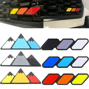 Three-color grille badge emblems for Toyota vehicles; mountain-style decals in white/blue, gray/blue, and yellow/orange