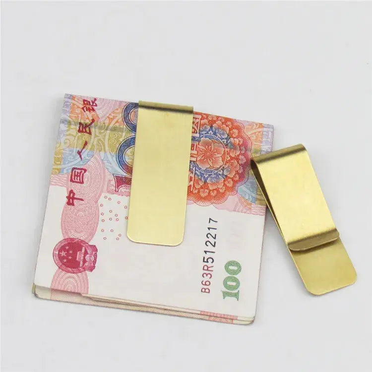 Two brass money clips by Simples Market on a stack of 100 yuan notes.