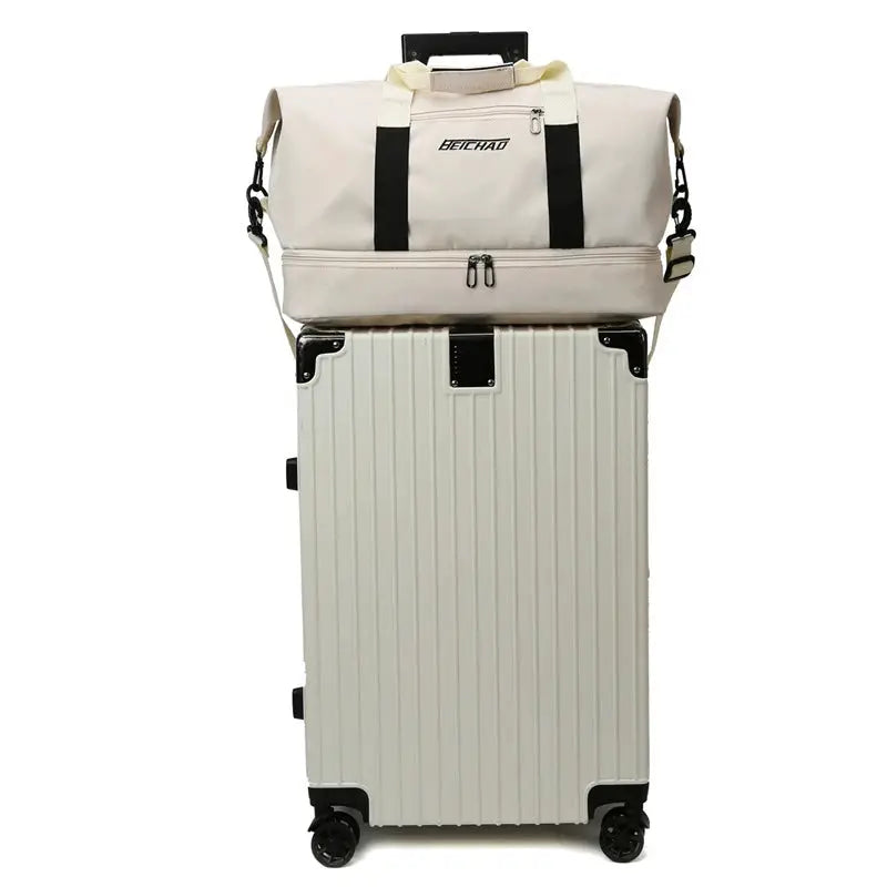 Expandable travel duffle bag BEICHAD, beige with black straps, atop a silver hard-shell suitcase