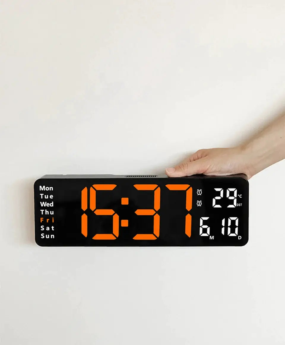 Large black digital wall clock with orange LED digits; left shows weekdays, right shows date and temperature.