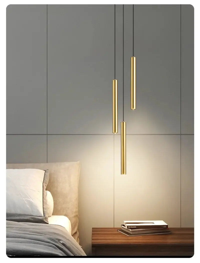 Bedside pendant LED lamp set of 3 in gold metal finish hanging over a wooden nightstand in a gray-panel bedroom.