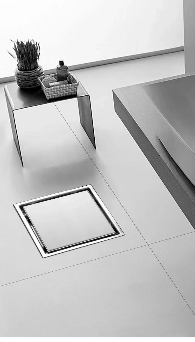 Large square stainless steel floor drain with chrome frame in a modern bathroom