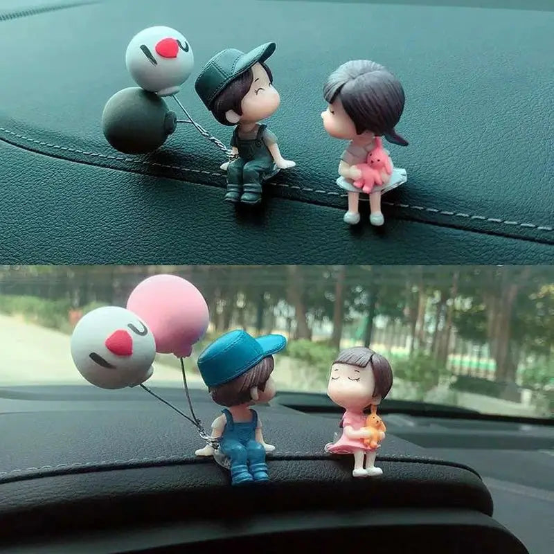 Car dashboard figurines: pair of cute cartoon couple with balloons; boy in cap and overalls, girl in pink dress