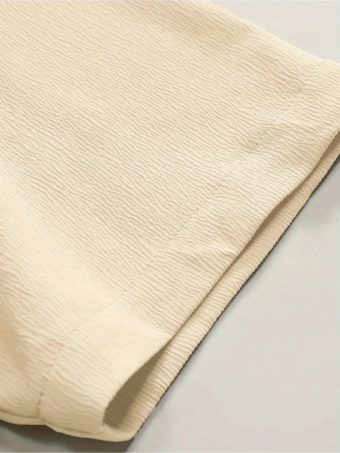 Beige textured linen-like fabric swatch with ribbed pattern, close-up view