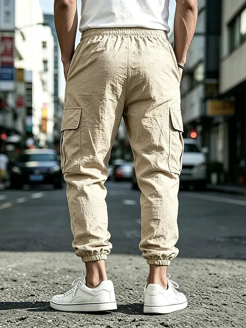 Men's cargo jogger pants in beige cotton-linen blend with elastic cuffs, drawstring waist and multiple cargo pockets.
