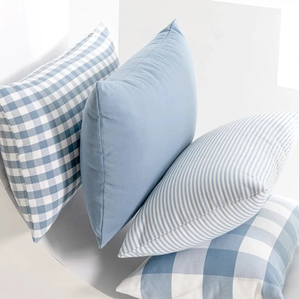 Pillow covers in light blue with plaid and striped patterns; four shown