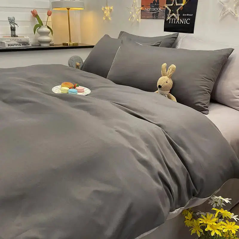 Dark gray duvet cover set on a double/queen bed with matching pillowcases and a bunny plush