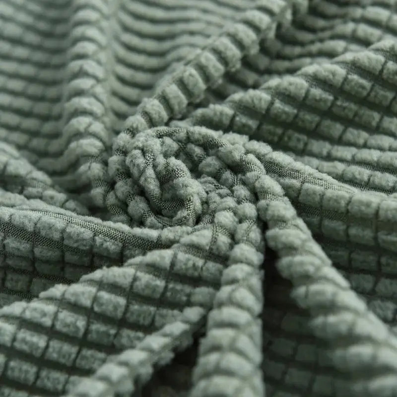 Thick elastic sofa cover in sage green chenille with a quilted grid texture