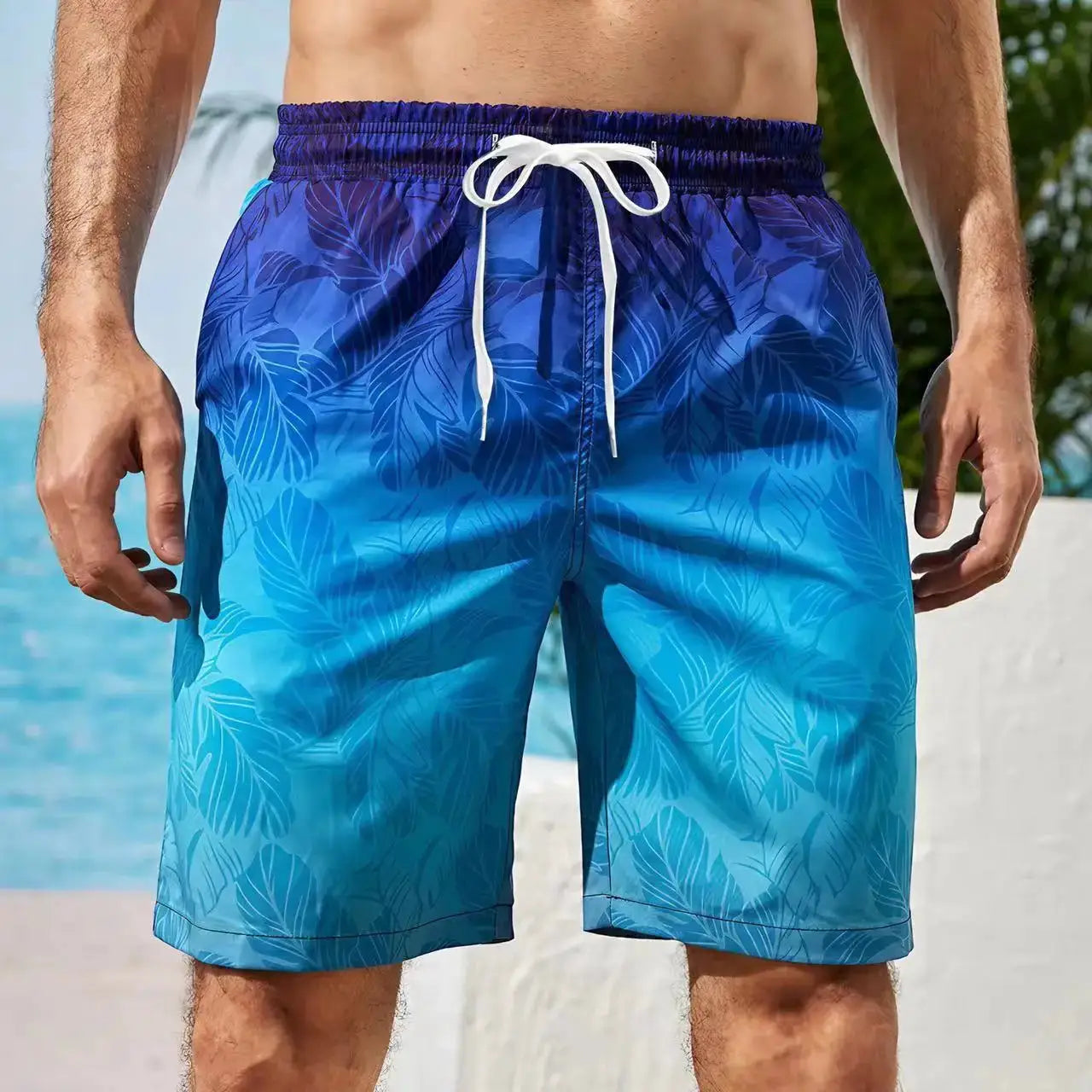 Men's board shorts in blue gradient palm-leaf print with white drawstring, quick-dry swim trunks.