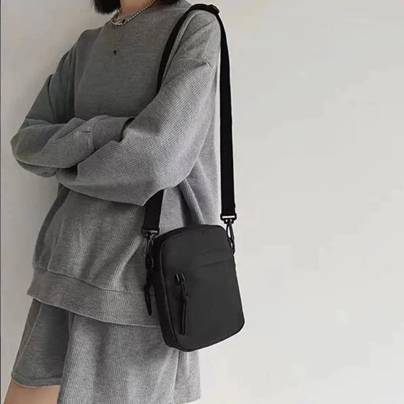 Crossbody bag; black compact single-shoulder phone bag with front zipper pocket