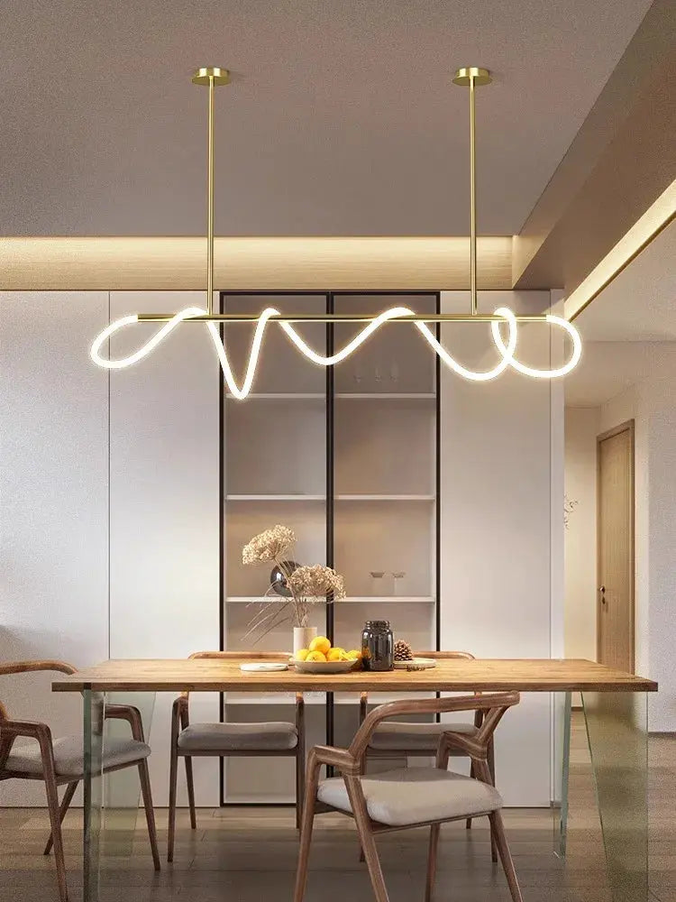 Simples Market Nordic pendant chandelier with brass finish and looping LED light over a wooden dining table.