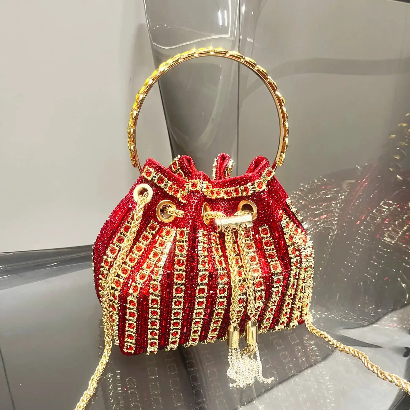 Red crystal-embellished bucket clutch evening bag with gold ring handle and tassel chains