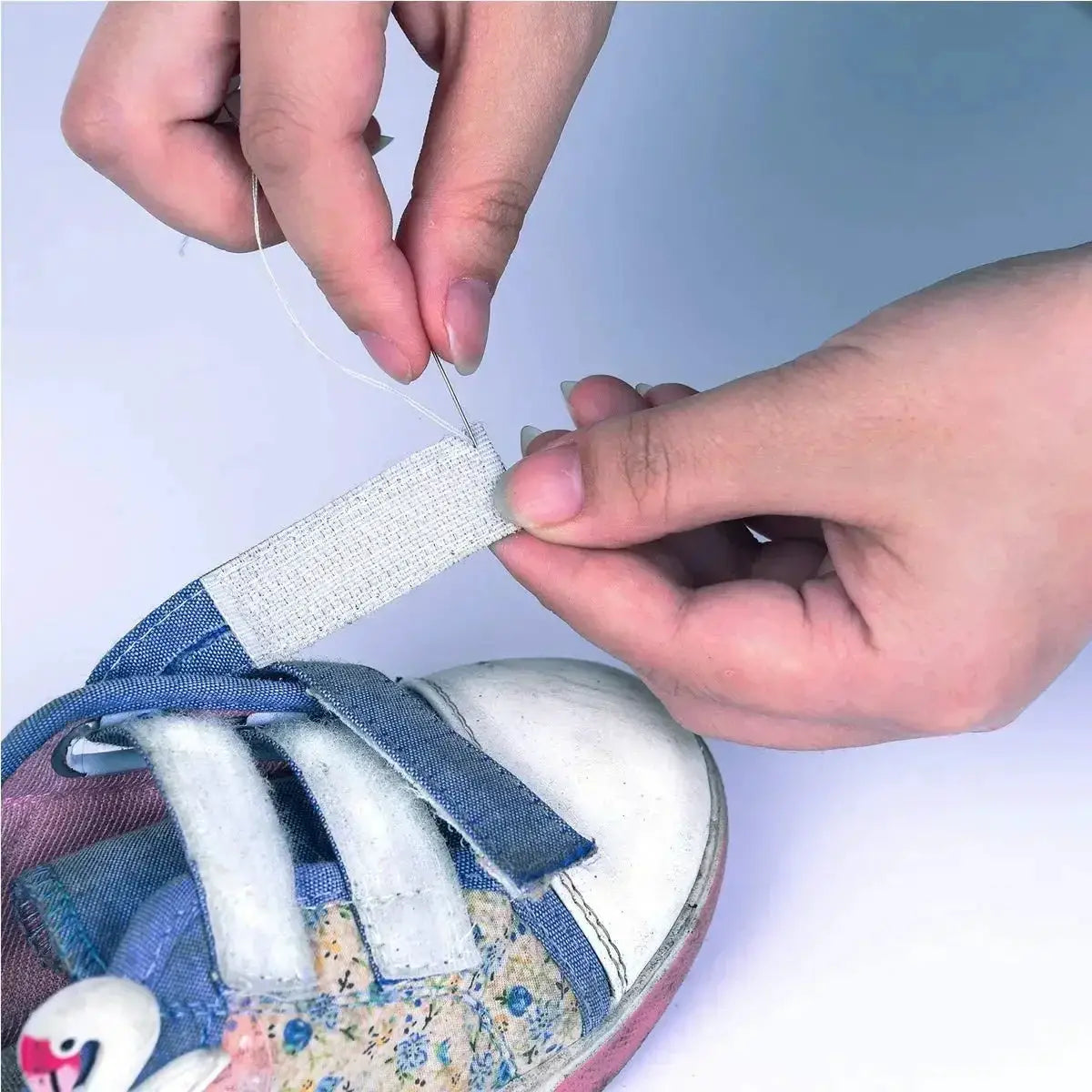 White fabric cable organizer strap being hand-sewn for cord management