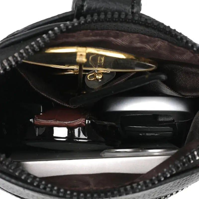 Black PU leather diagonal cross bag with double-layer interior and visible gold-tone sunglasses inside