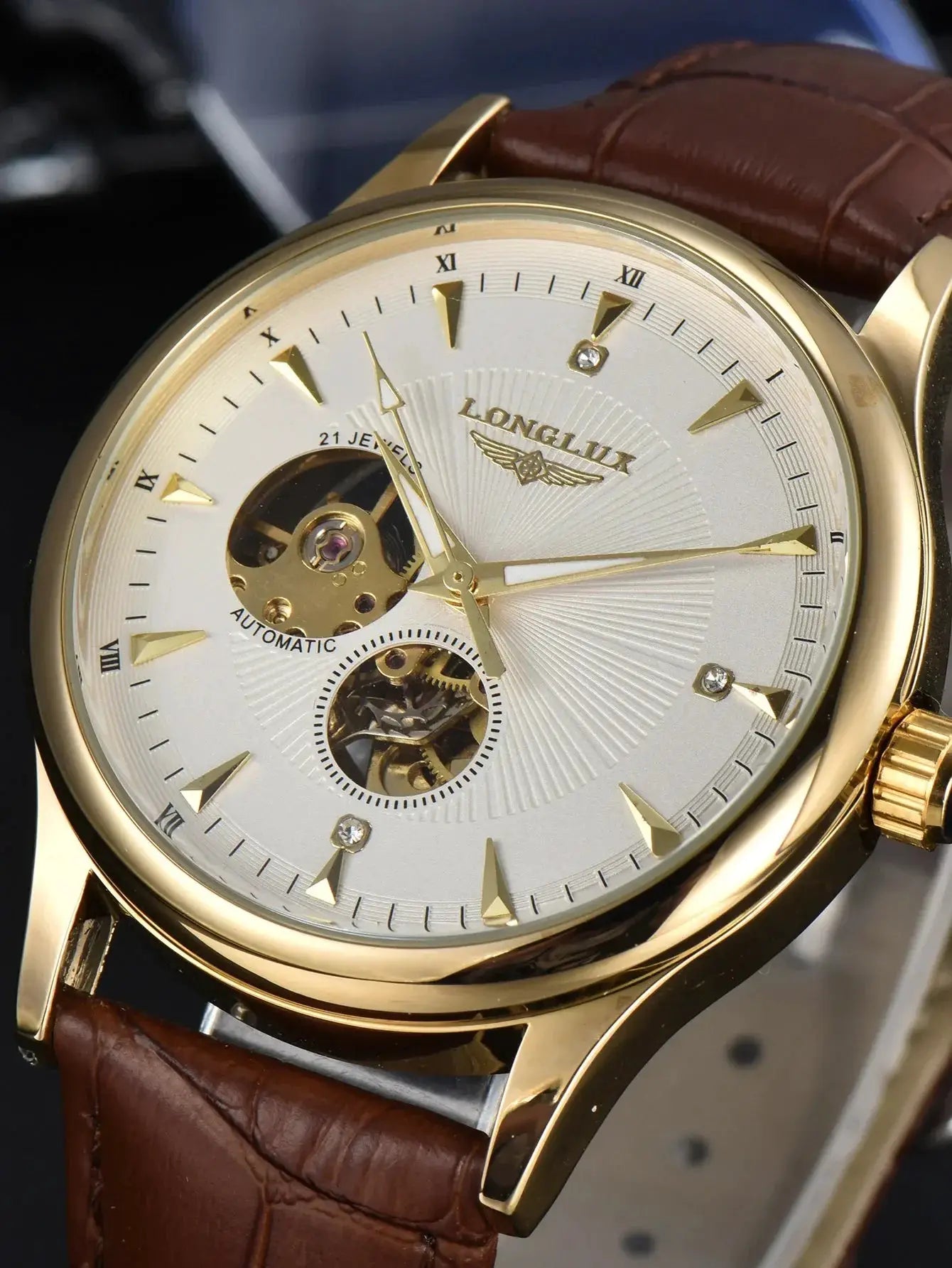 Automatic skeleton watch with gold-tone case, brown leather strap and Roman numeral dial.