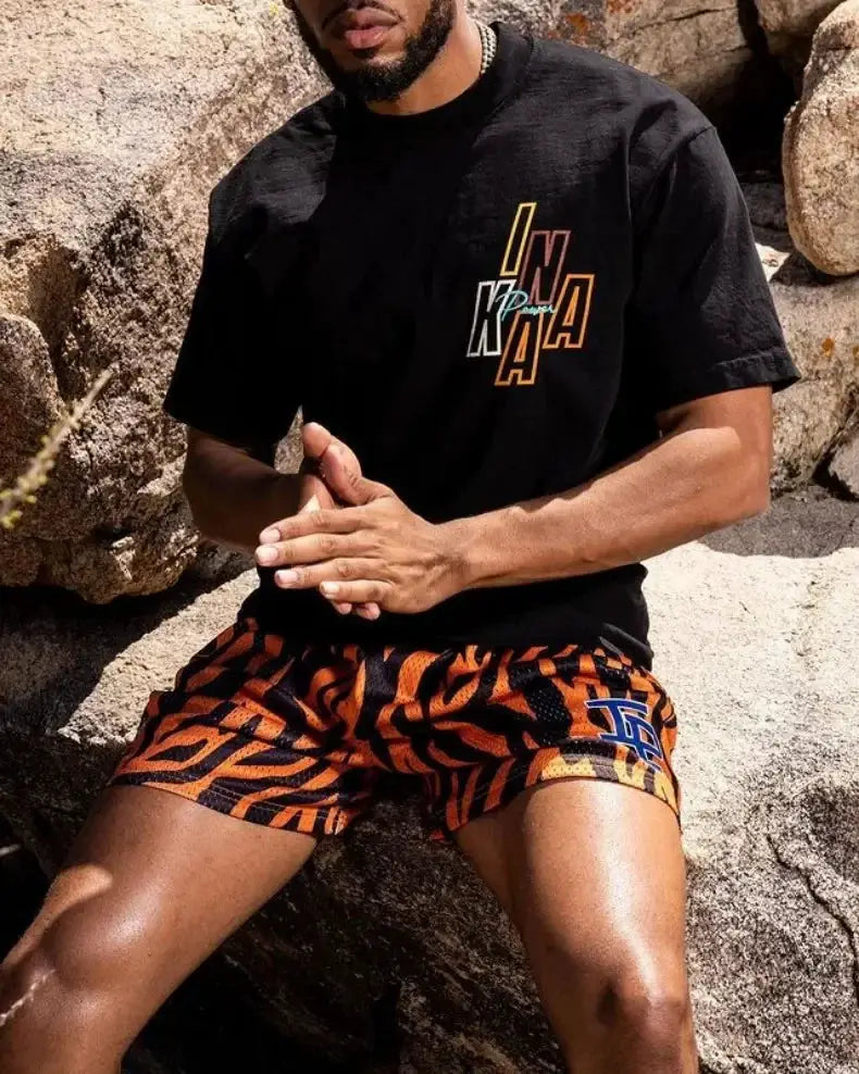 Men's athletic shorts with orange tiger-print pattern and blue LA logo.