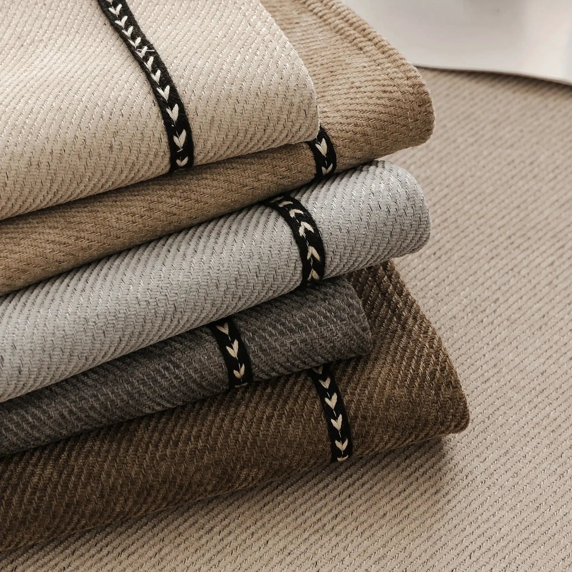 Vintage-style chenille sofa slipcover fabric samples in beige, gray, and brown tones with black braided trim.