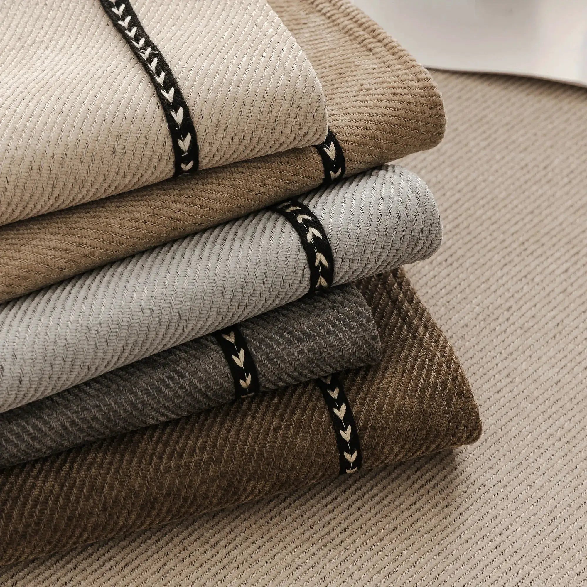 Vintage-style chenille sofa slipcover fabric samples in beige, gray, and brown tones with black braided trim.