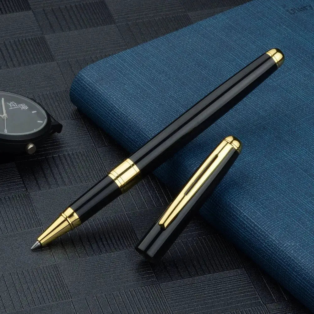 Ballpoint pens, two black with gold caps and clips resting on a blue textured notebook