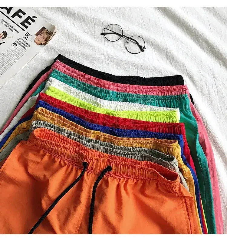 Men's beach board shorts in assorted colors, stacked with drawstring waists.