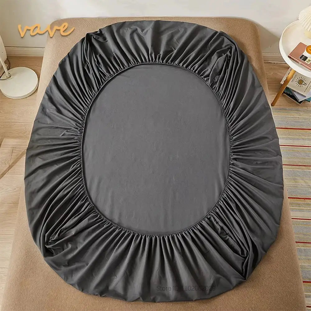 Full-size dark gray cotton fitted sheet with elastic bands shown on a bed.
